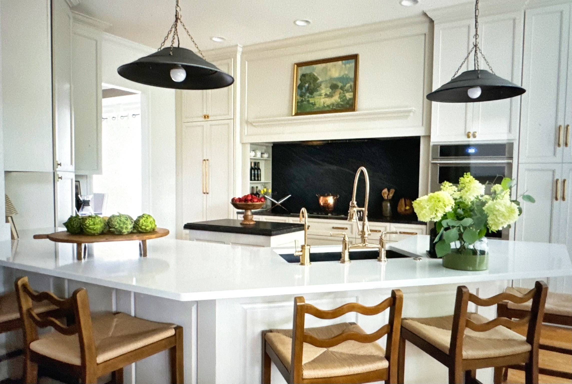 White kitchen with brass fixtures and slate cooking niche